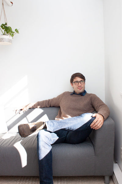 Load image into Gallery viewer, man on couch with crossed leg wearing blue jeans and handknit brown pullover
